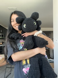 a woman holding a black stuffed toy dragon