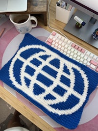 a blue and white crocheted blanket on a desk